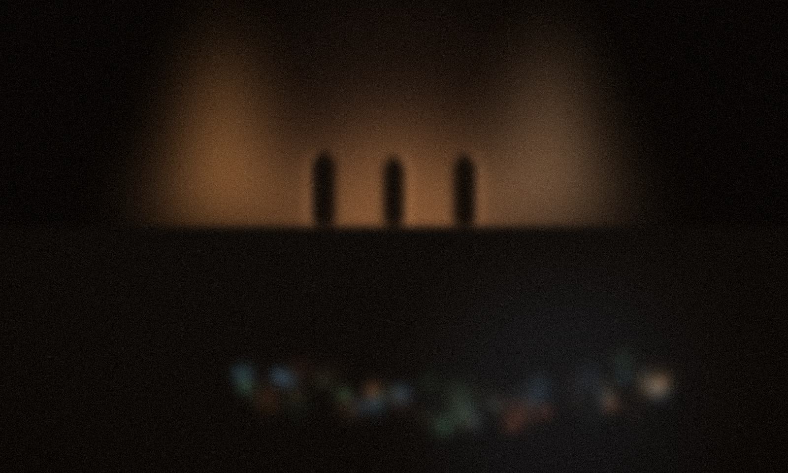 Una sala fosca durant un concert, l’escenari il·luminat al fons i la taula de so brillant entre el públic